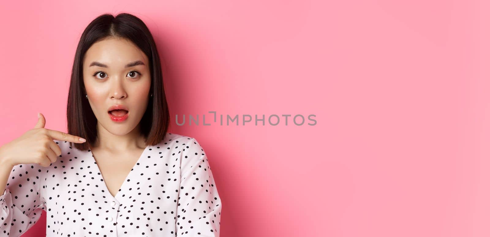 Image of confused asian woman pointing at herself, drop jaw and staring questioned at camera, standing over pink background by Benzoix