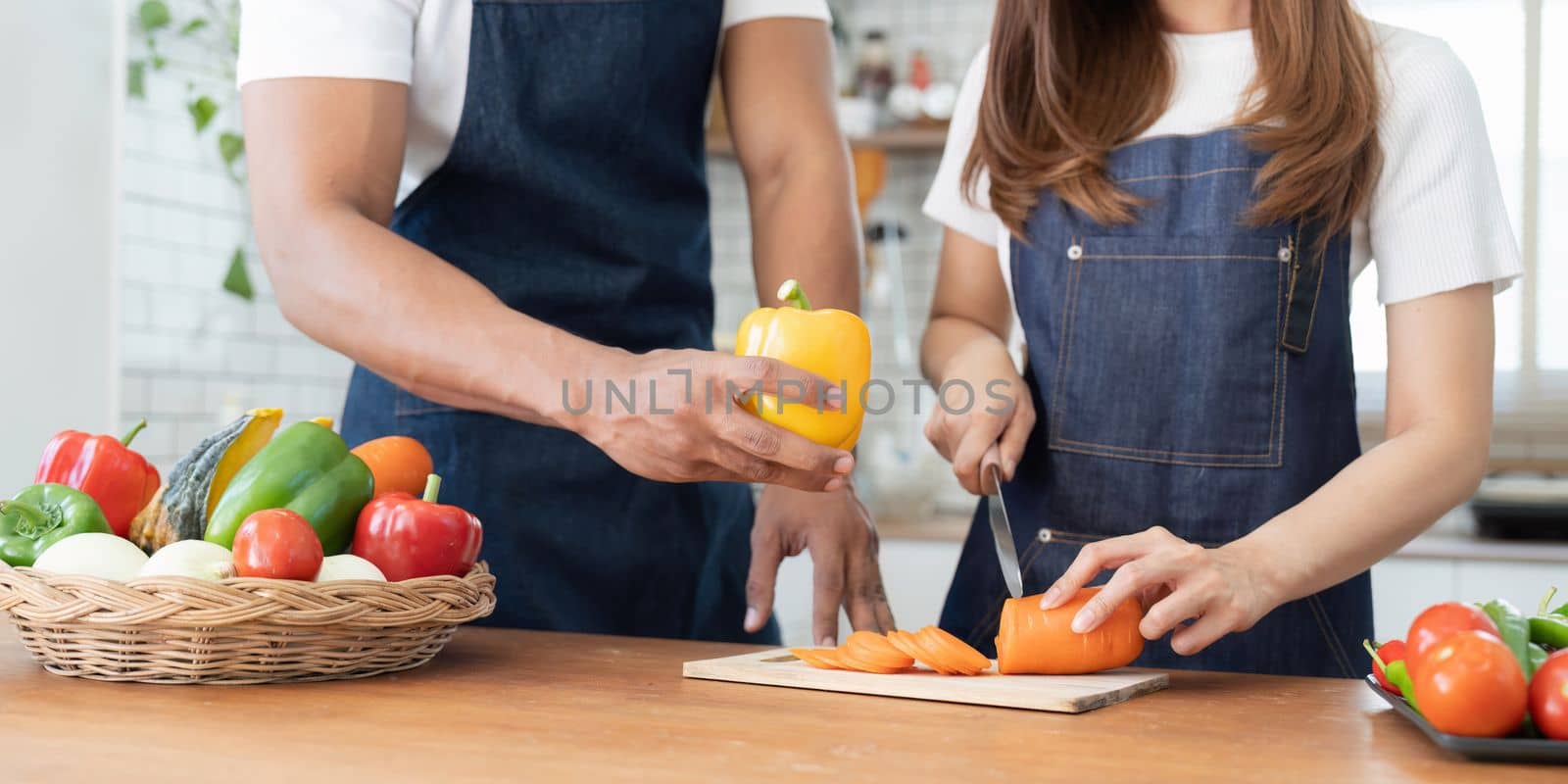 Happy couple preparing food together in kitchen at home ready to cook together by nateemee