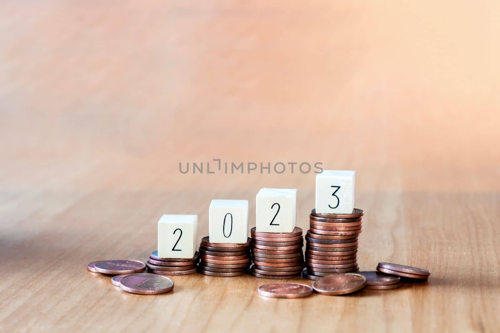 wooden cube year 2023 on top stack of coins with sky blue background and copy space. saving money and financial plan concept for investment in new year 2023. close up