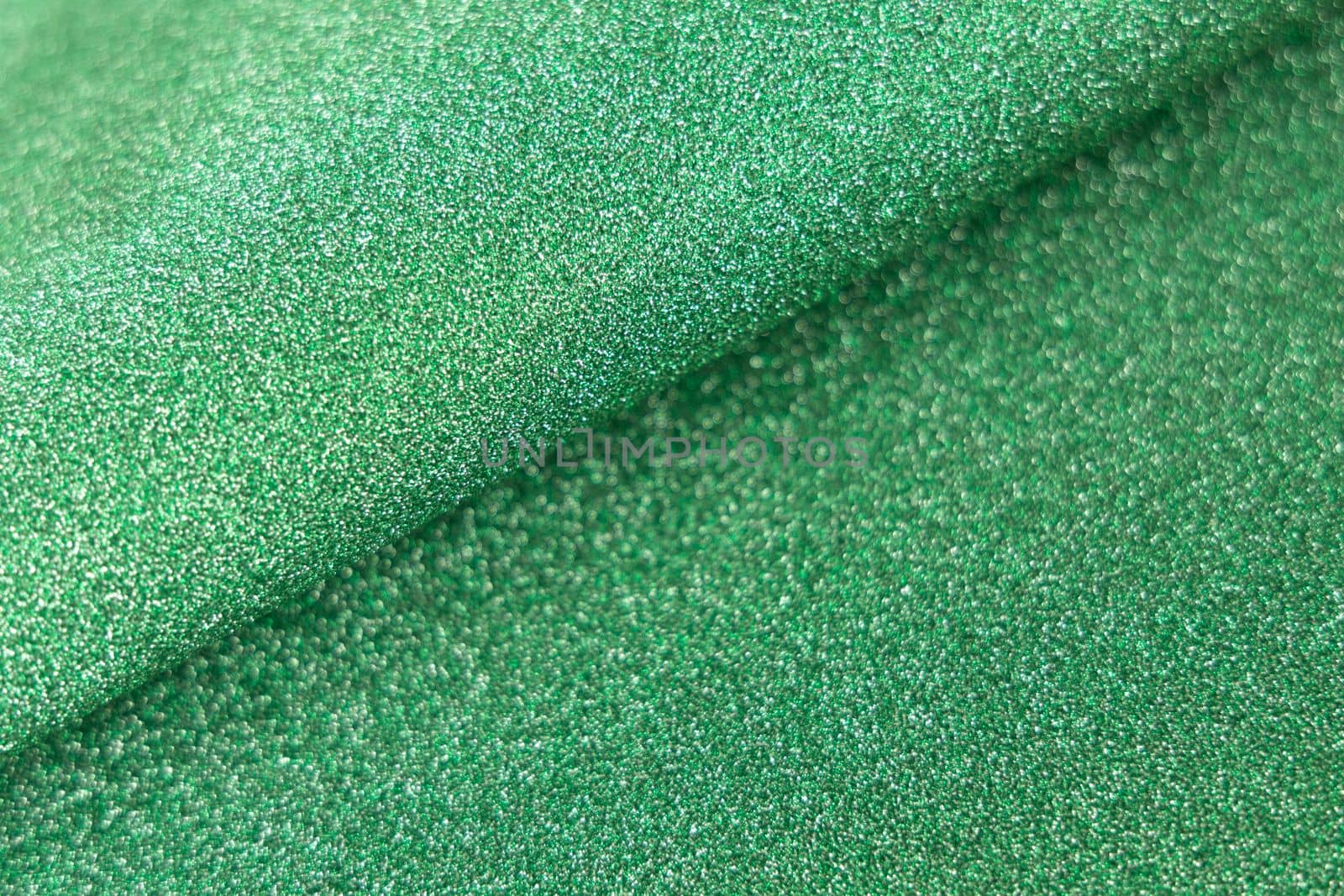 Green shiny glitter wave paper texture. Glow luxurious fabric. Light green color st Patric background. Empty space
