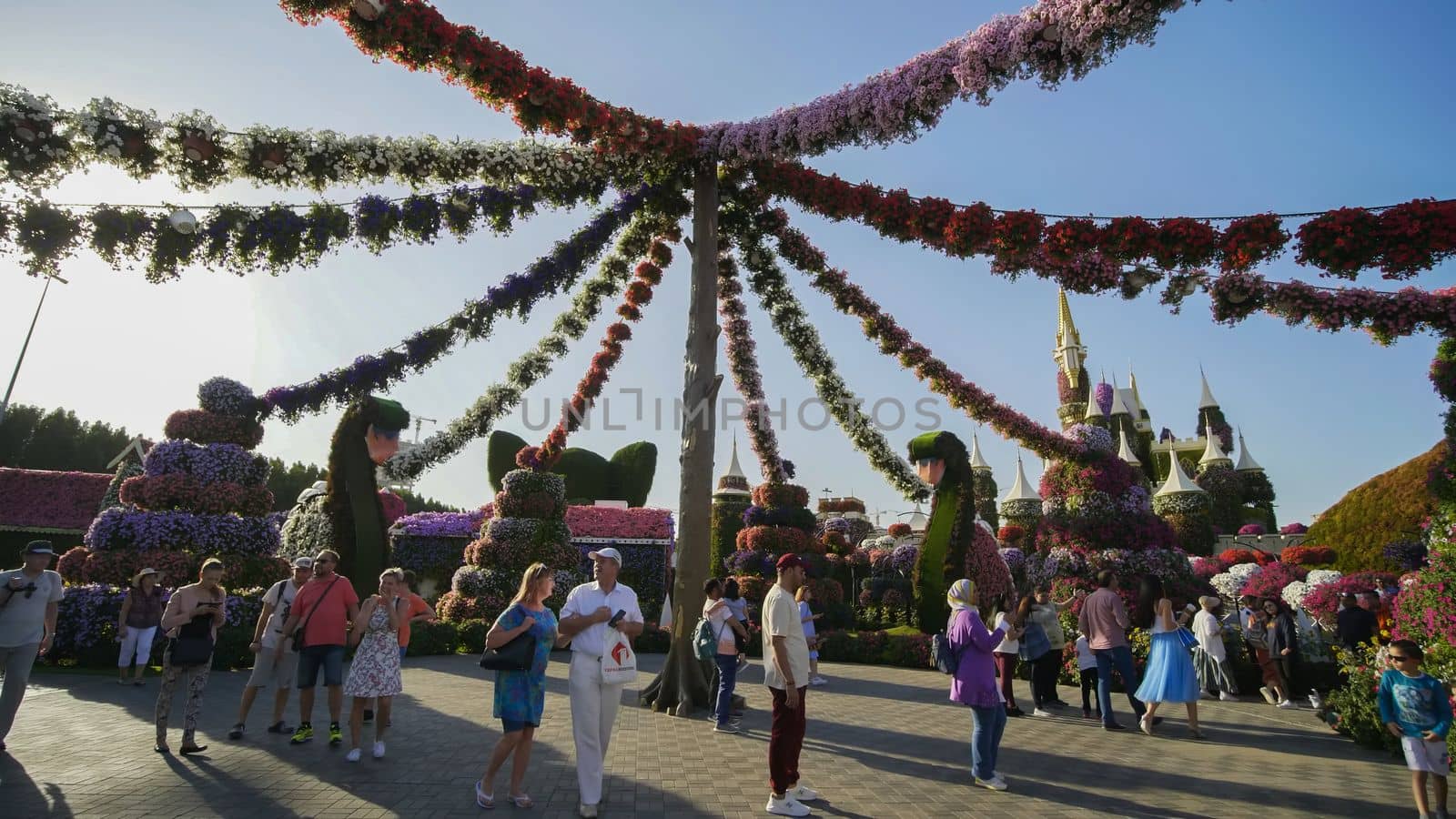 Hanging garlands of fresh flowers in a city park with visitors