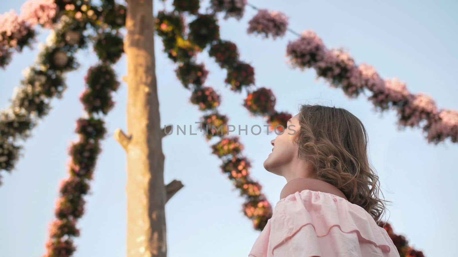 Girl on the background of hanging daisies of fresh flowers in a city park