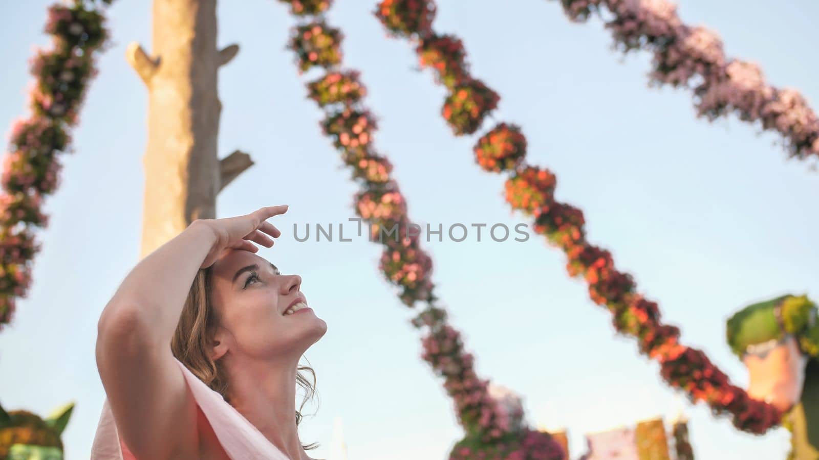 Girl on the background of hanging daisies of fresh flowers in a city park in Dubai