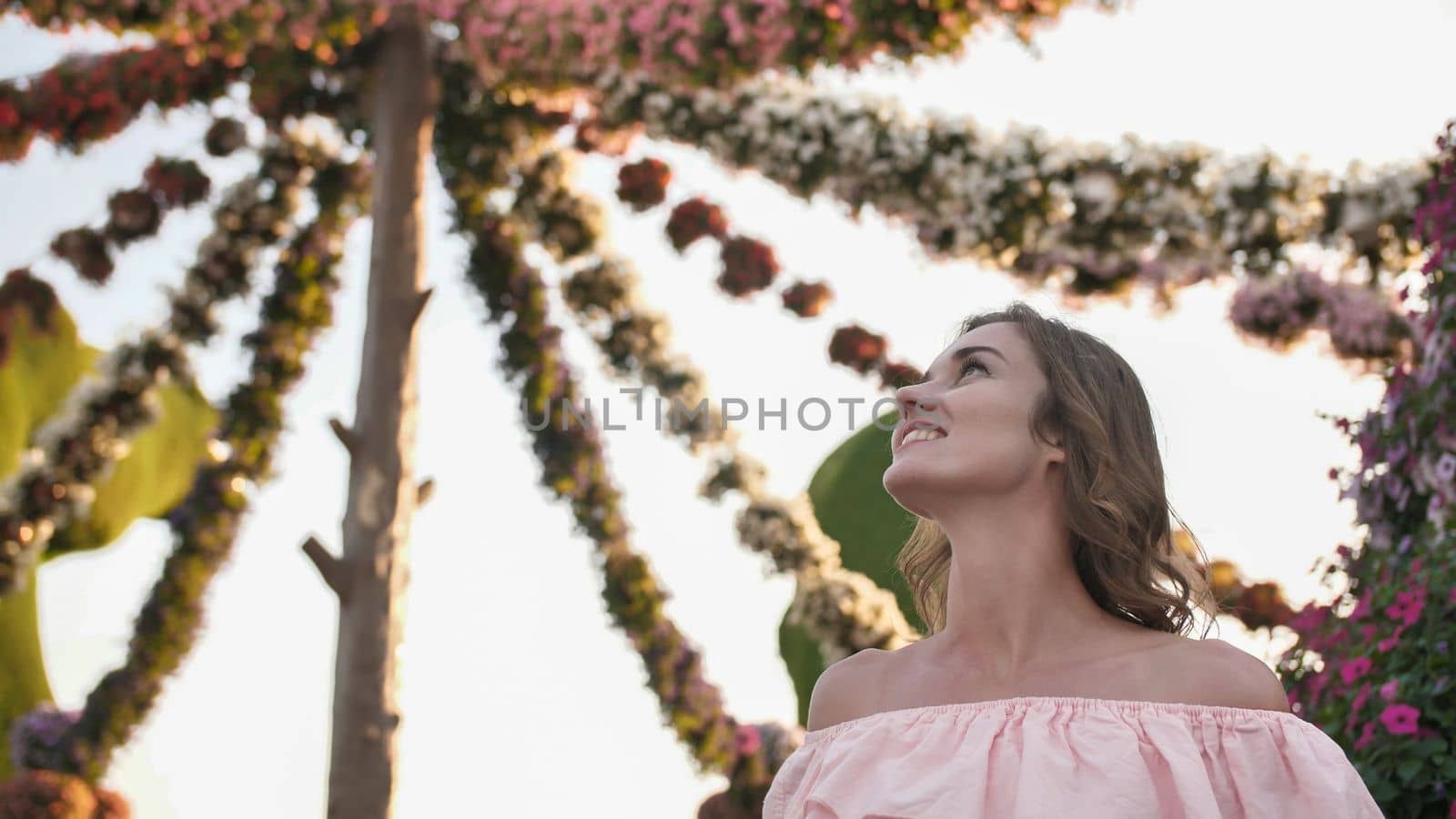 Girl on the background of hanging daisies of fresh flowers in a city park