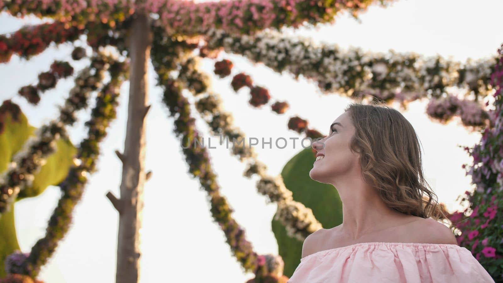Girl on the background of hanging daisies of fresh flowers in a city park