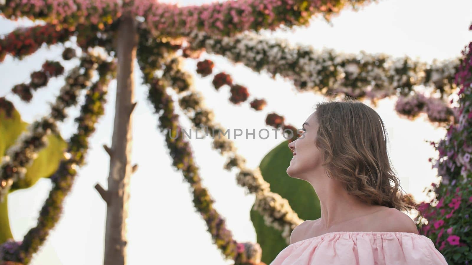 Girl on the background of hanging daisies of fresh flowers in a city park in Dubai