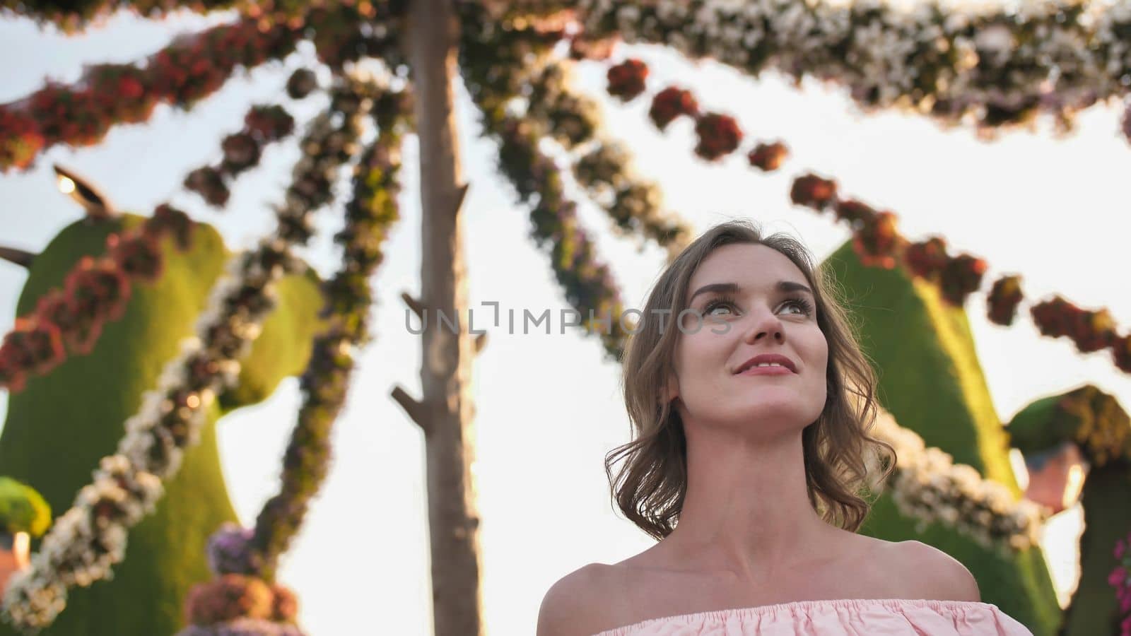 Girl on the background of hanging daisies of fresh flowers in a city park in Dubai