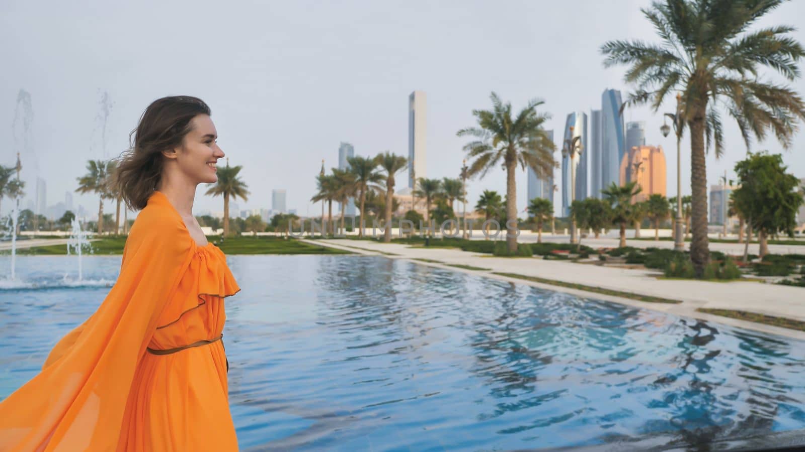 A girl in an orange dress walks through the evening Abu Dhabi. UAE