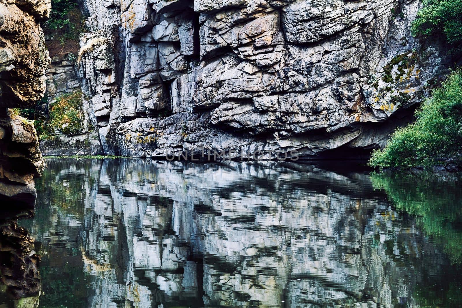 Deep rocky silver canyon with smoothly flowing water and reflection close up by jovani68