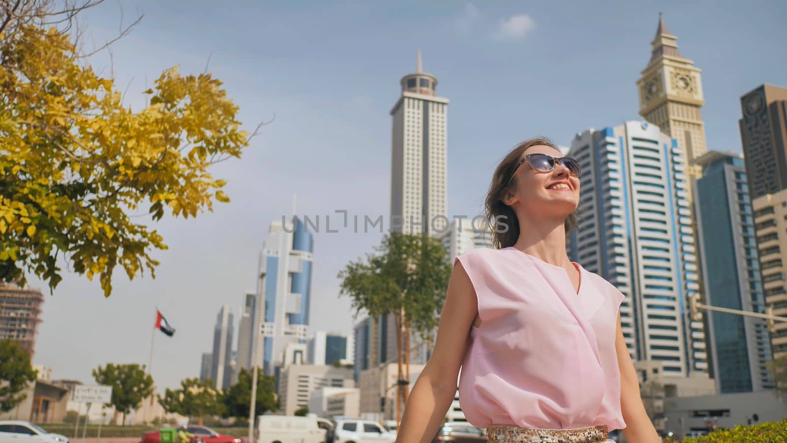 Happy girl walks in the center of Dubai against the background of skyscrapers