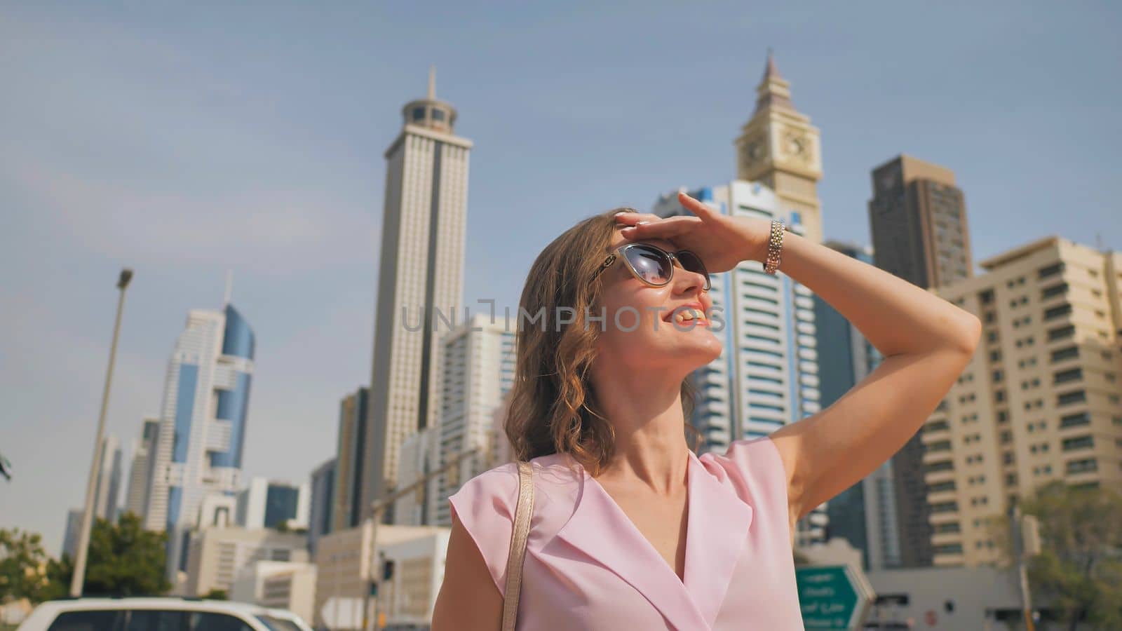 Happy girl walks in the center of Dubai against the background of skyscrapers