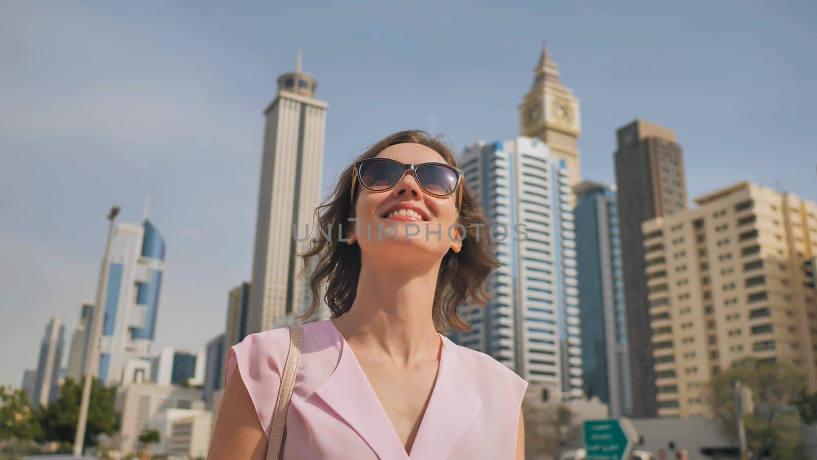 Happy girl walks in the center of Dubai against the background of skyscrapers