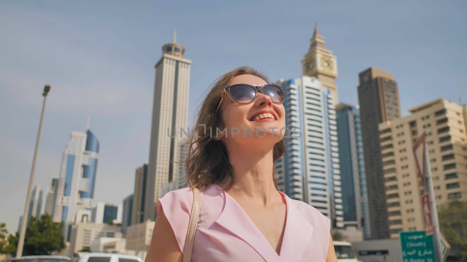 Happy girl walks in the center of Dubai against the background of skyscrapers
