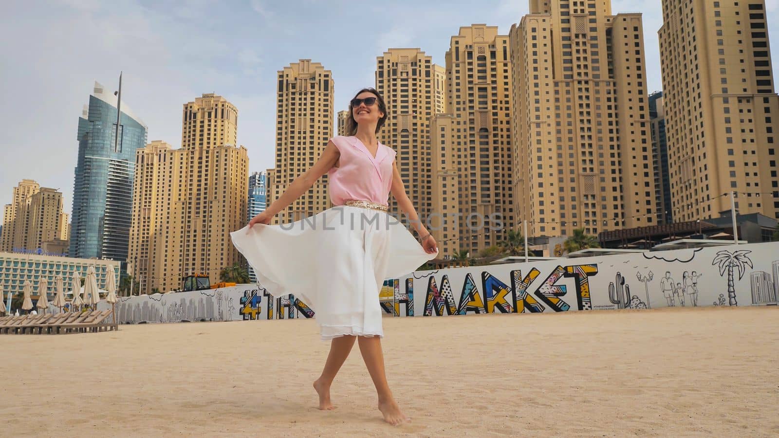 Happy girl walks in the center of Dubai against the background of skyscrapers