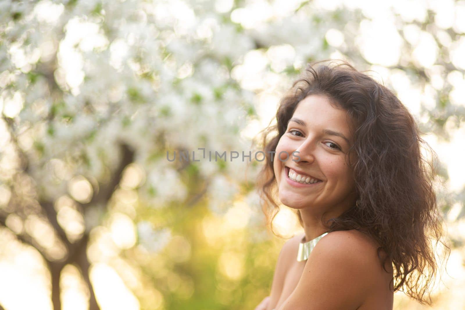A young brunette girl poses with a blossoming cherry branch.