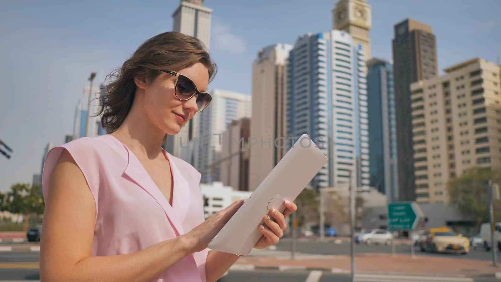 A girl works on a tablet against the background of skyscrapers of a metropolis