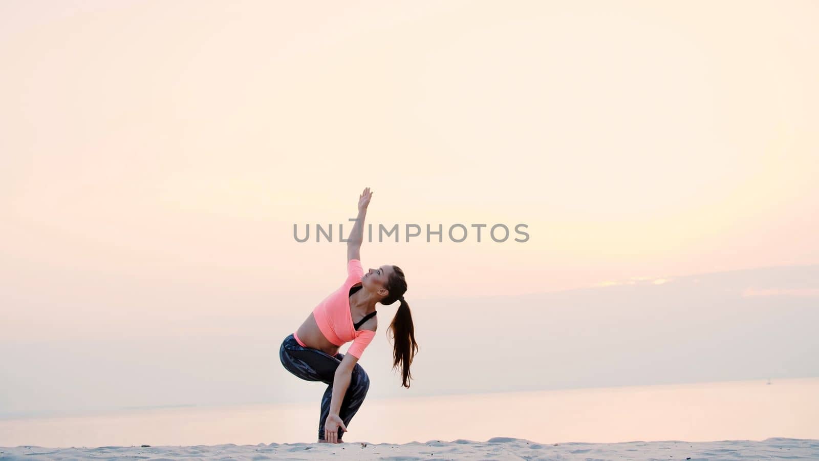 Healthy, young beautiful woman meditating, practicing yoga on the sea beach, at sunrise, Makes exercises for balance and coordination, deep muscle tone. High quality photo