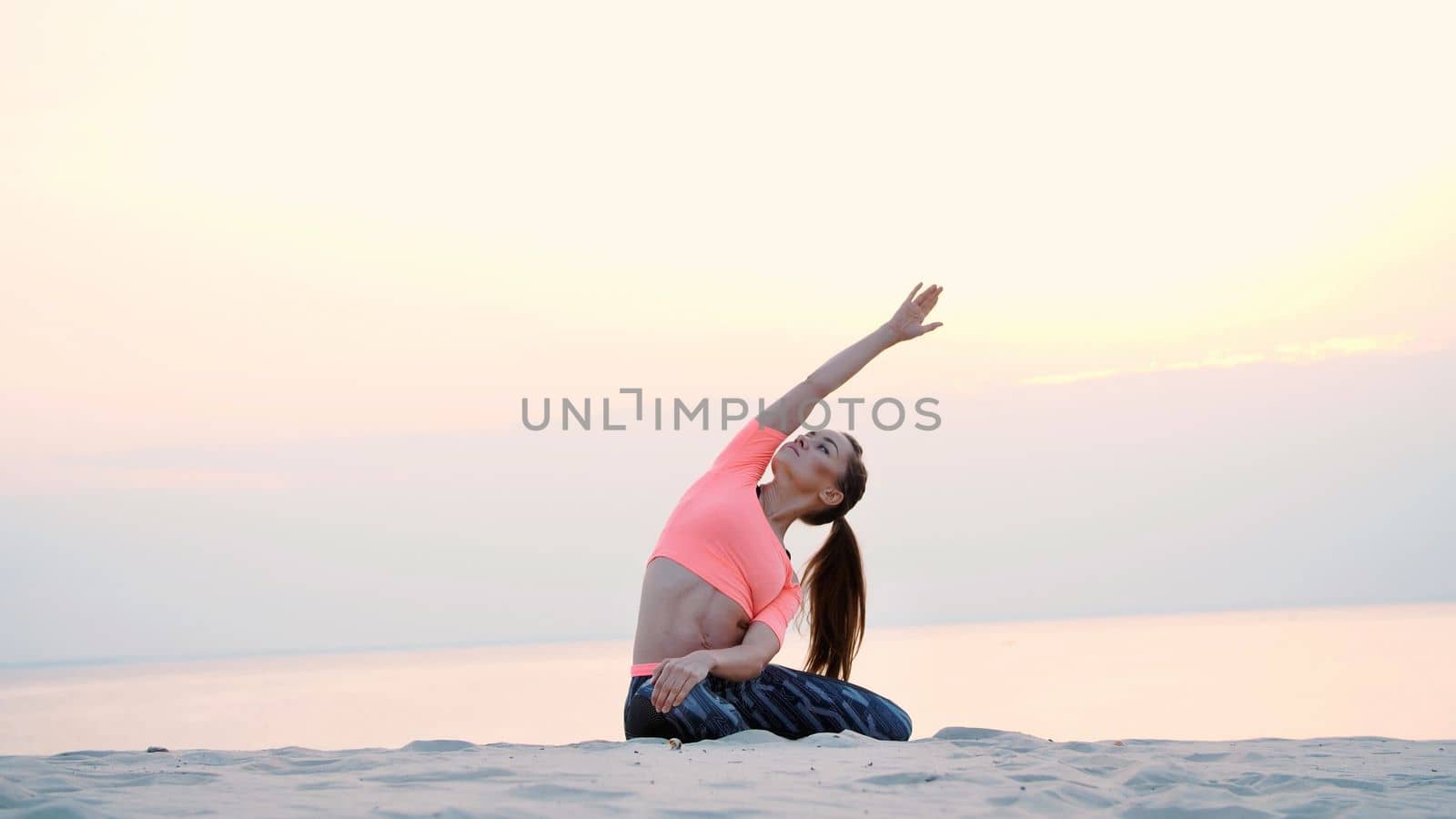 Woman sitting in relaxation yoga pose at the sea beach. at sunrise. Relaxes the muscles, the mind, acquires the harmony of the soul and body by djtreneryay