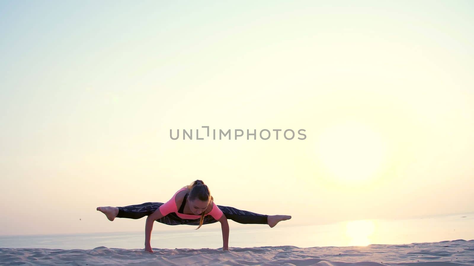 Healthy, young beautiful woman meditating, stretching, practicing yoga on the sea beach, at sunrise, Makes exercises for balance and coordination, deep muscle tone. High quality photo