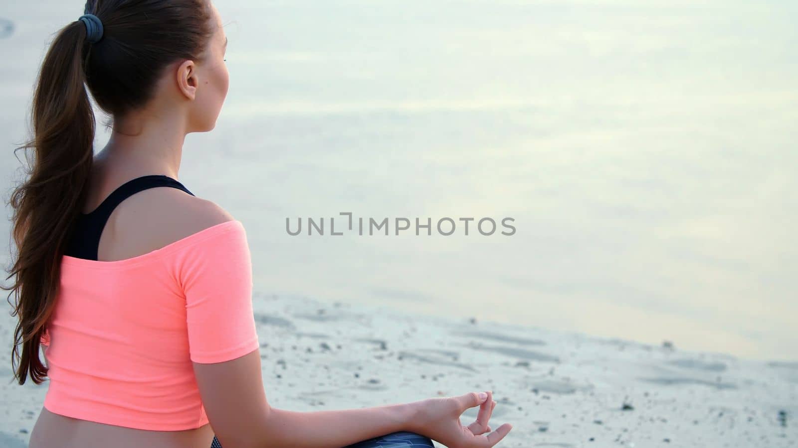 Woman sitting in relaxation yoga pose at the sea beach. Closeup. High quality photo