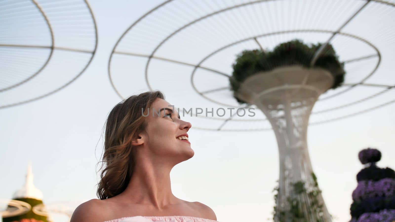 Girl on the background futuristic metal flowers in Dubai Miracle Garden Park