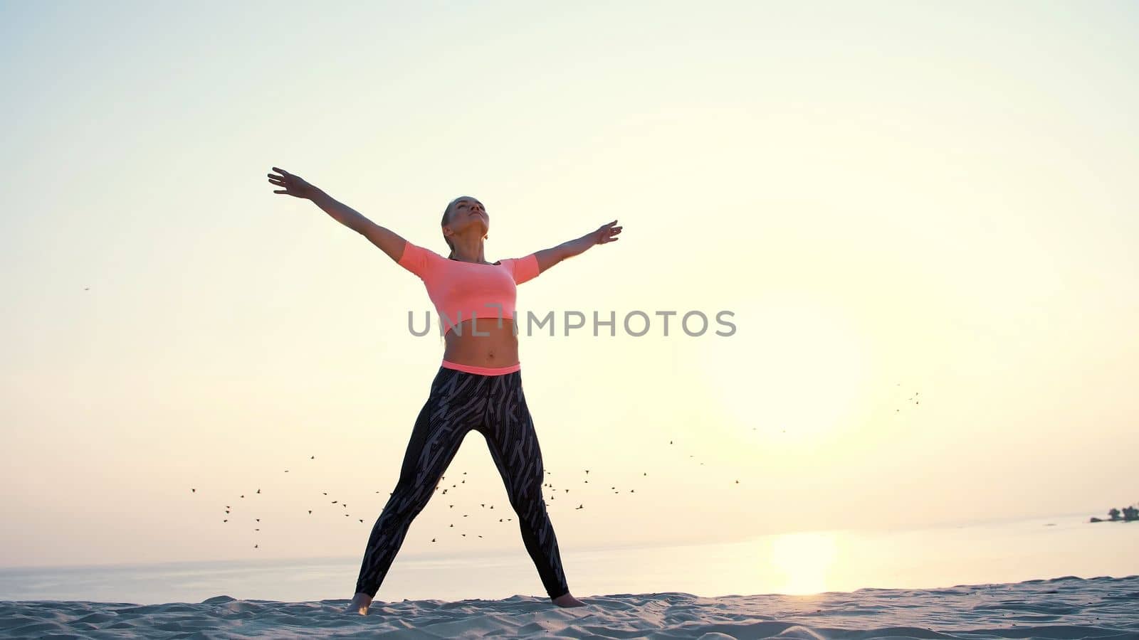 Healthy, young beautiful woman meditating, stretching, practicing yoga on the sea beach, at sunrise, Makes exercises for balance and coordination, deep muscle tone. High quality photo