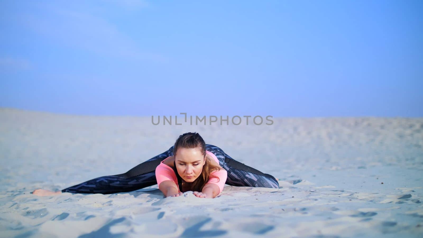 Healthy, young beautiful woman stretching, practicing yoga on the beach, at sunrise, Makes exercises for balance and coordination, deep muscle tone. relaxation of muscles, mind. High quality photo