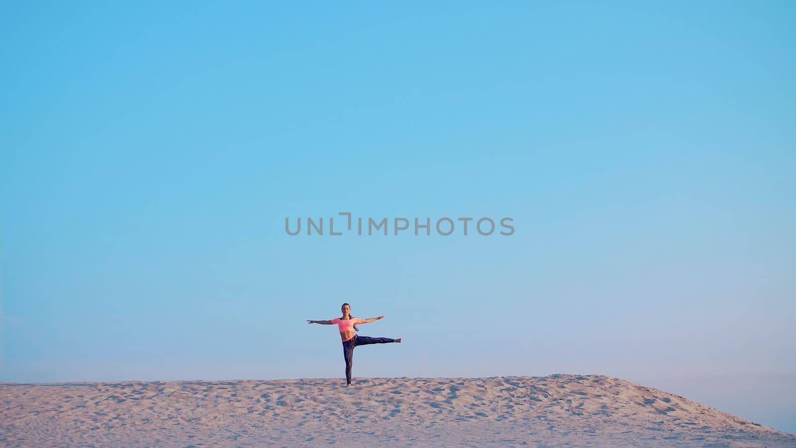 Healthy, young beautiful woman meditating, stretching, practicing yoga on the sea beach, at sunrise, Makes exercises for balance and coordination, deep muscle tone. High quality photo