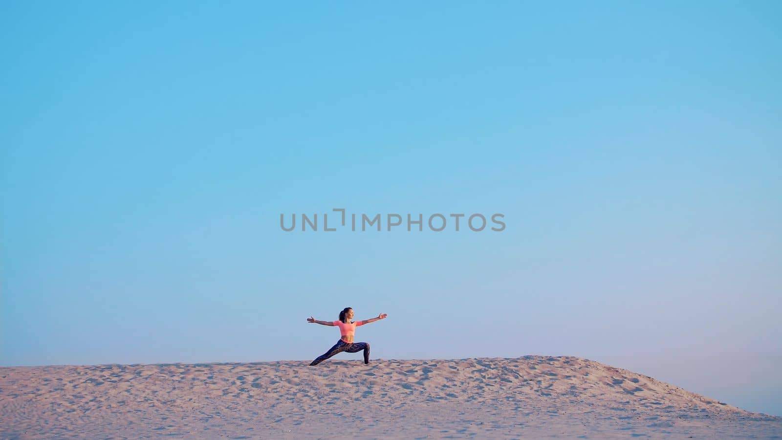 Healthy, young beautiful woman meditating, stretching, practicing yoga on the sea beach, at sunrise, Makes exercises for balance and coordination, deep muscle tone. High quality photo