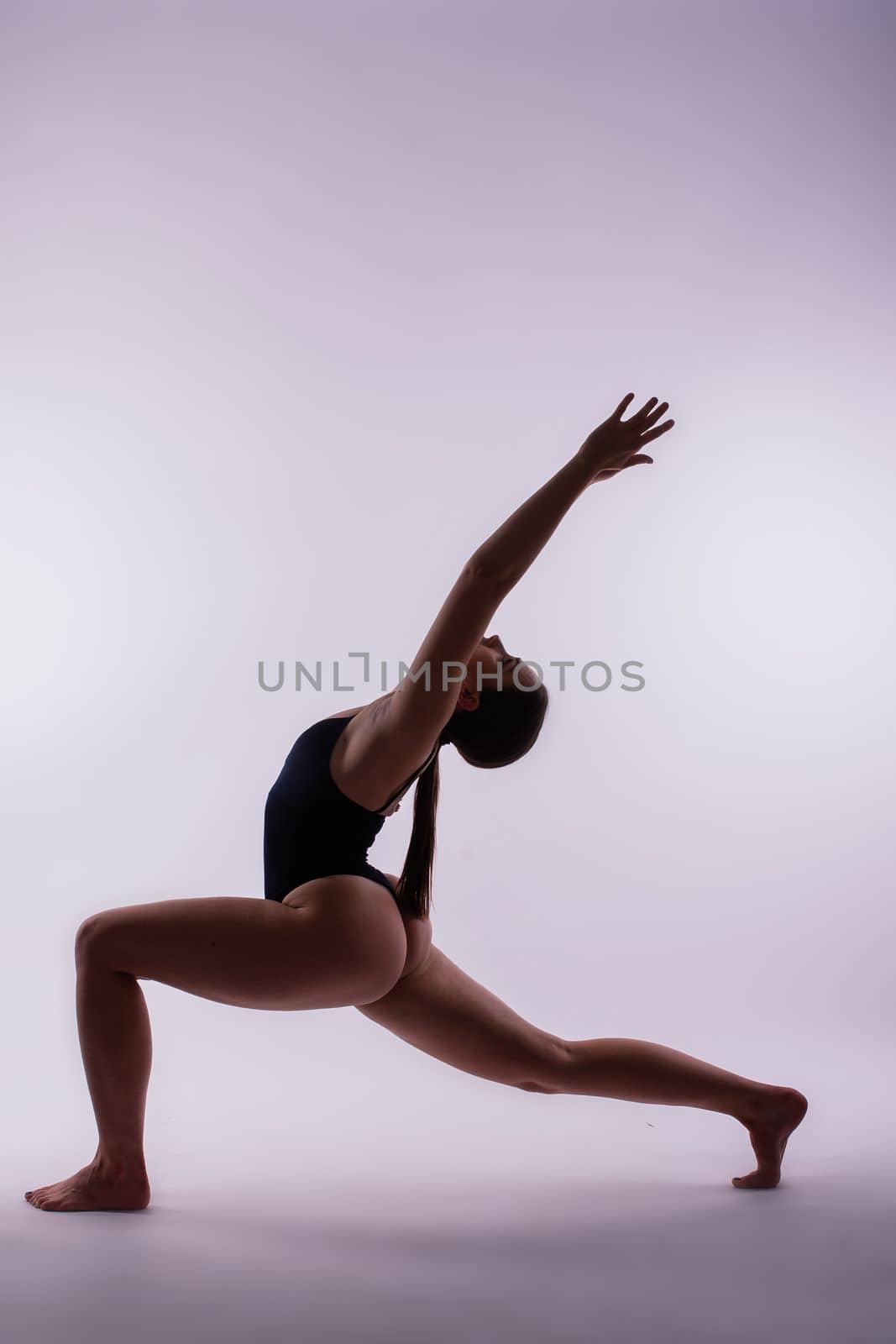 Portrait of beautiful young woman wearing black sportswear working out in studio. Full length. by Zelenin