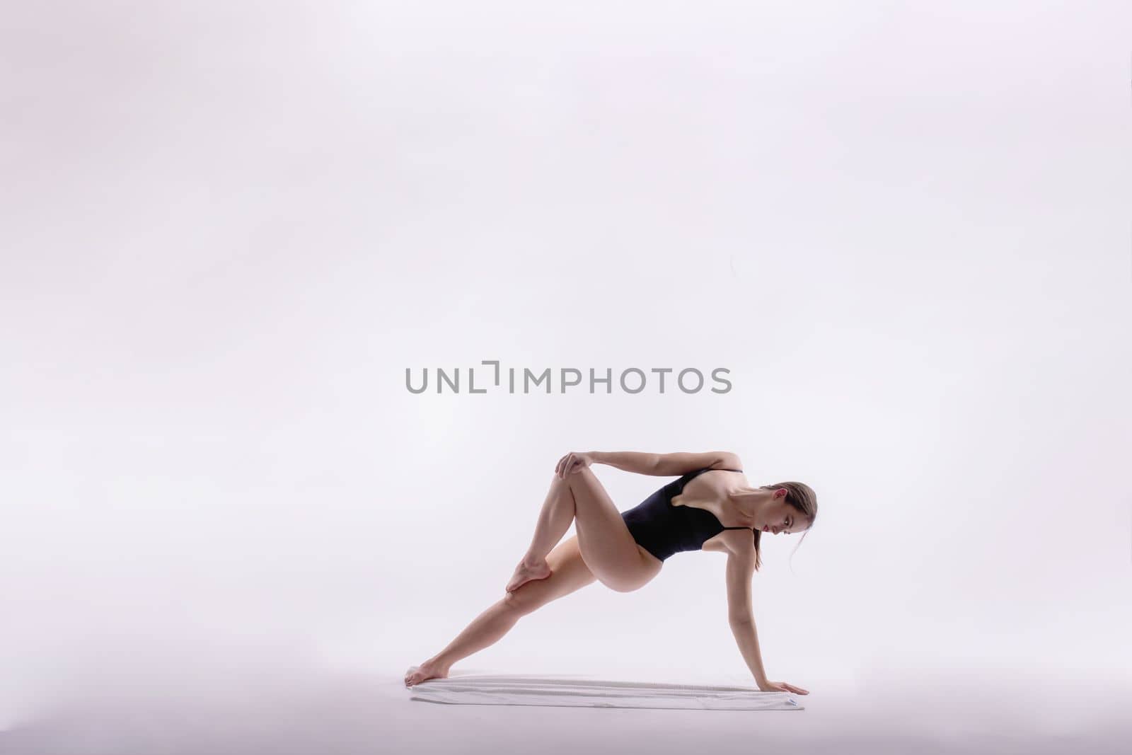 Portrait of a beautiful young woman wearing black sportswear working out in studio. Full length.