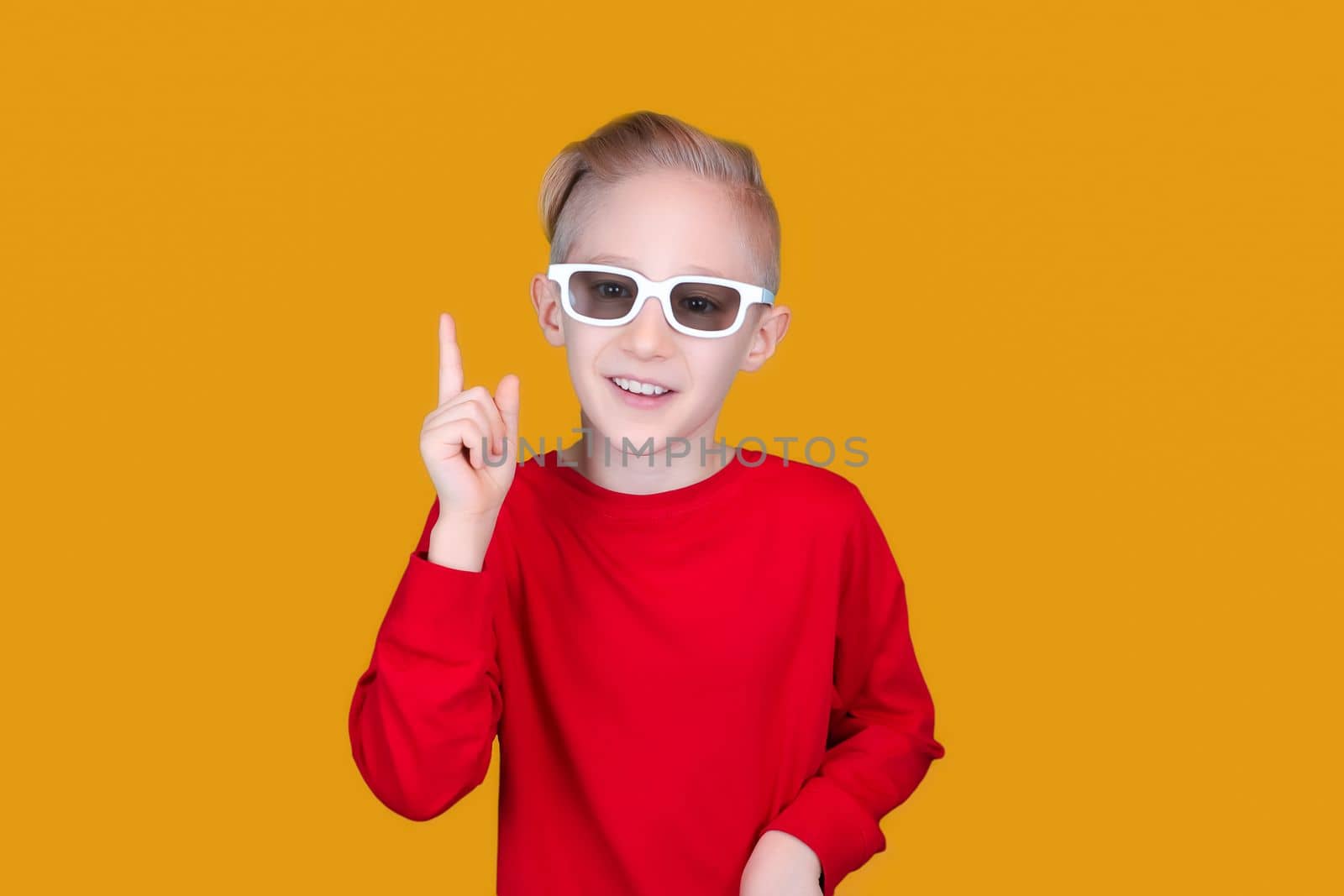 a child in children's 3D glasses raised his finger up on a yellow background
