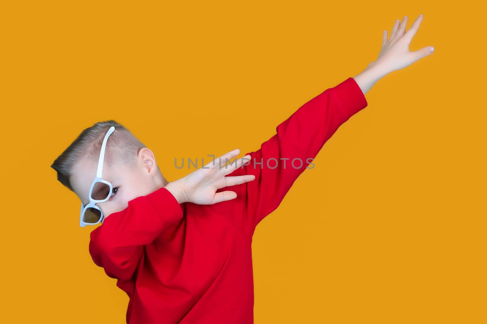 a cheerful child in children's 3D glasses points with his hands to the side