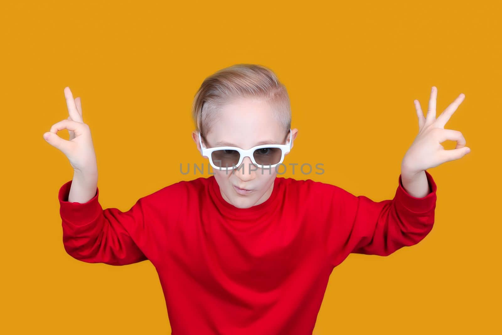 child in 3D movie glasses shows hand gesture OK