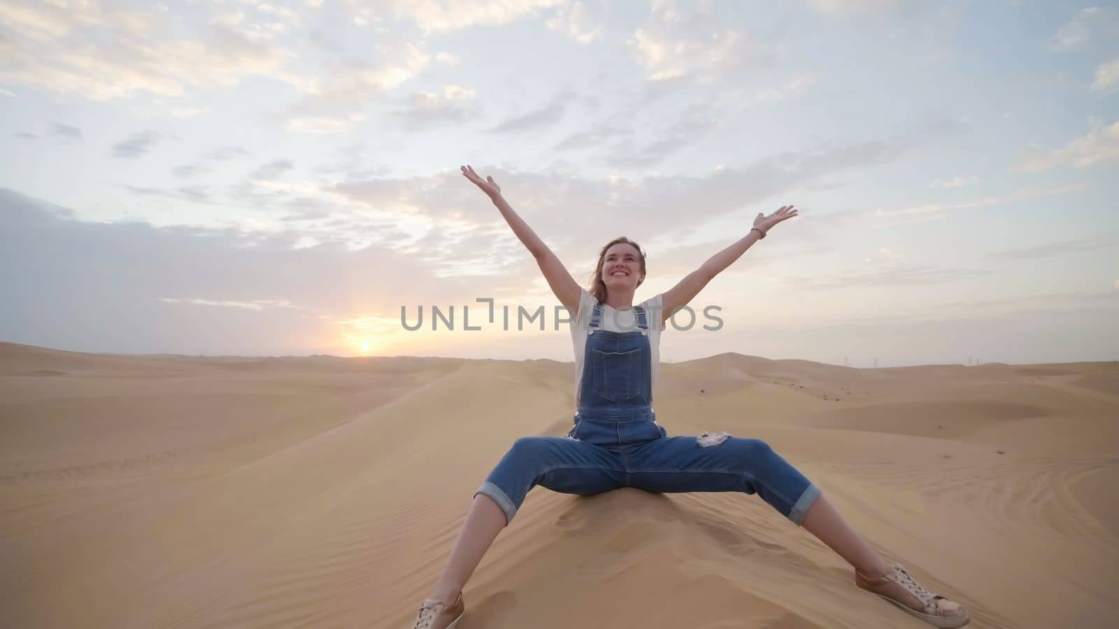 A happy girl in the desert of the Arab Emirates throws up sand