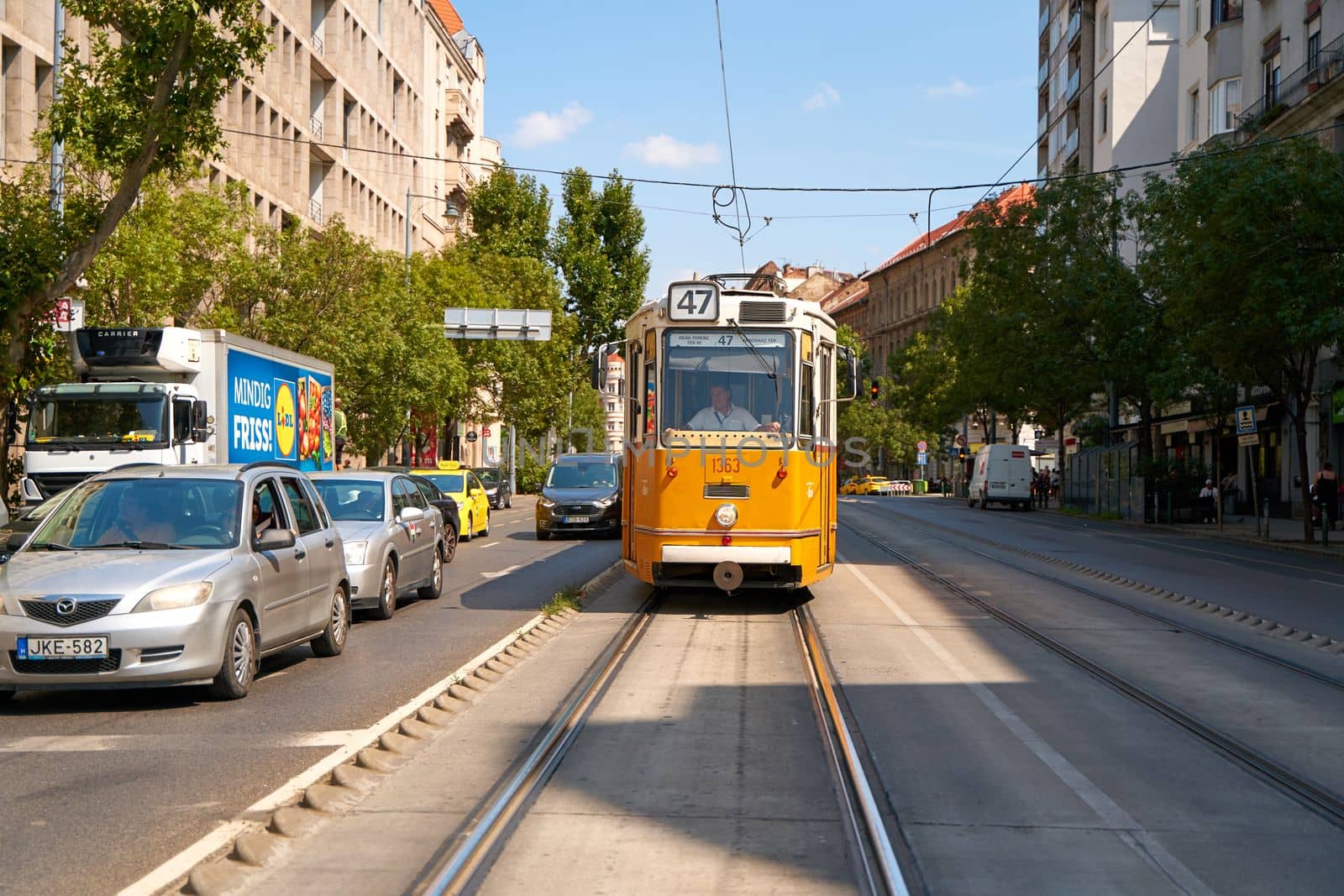 An old tram is traveling along a street in a modern city. Budapest, Hungary - 08.25.2022