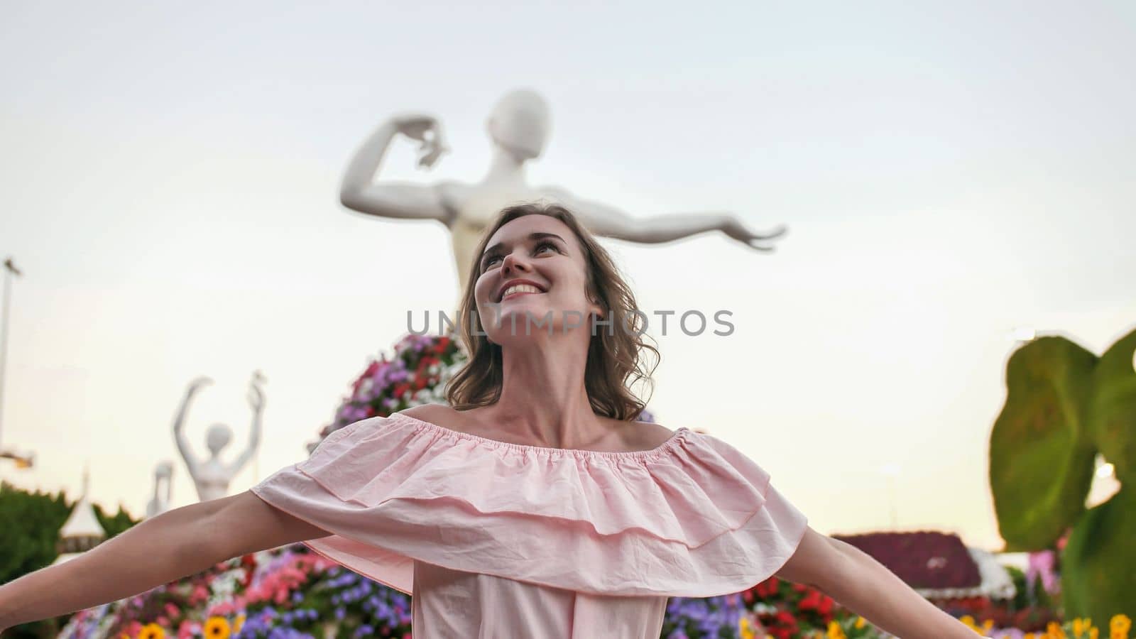 Girl posing on the background of the exposition of the statue of a ballerina. In the Garden of Miracles and Flowers in Dubai