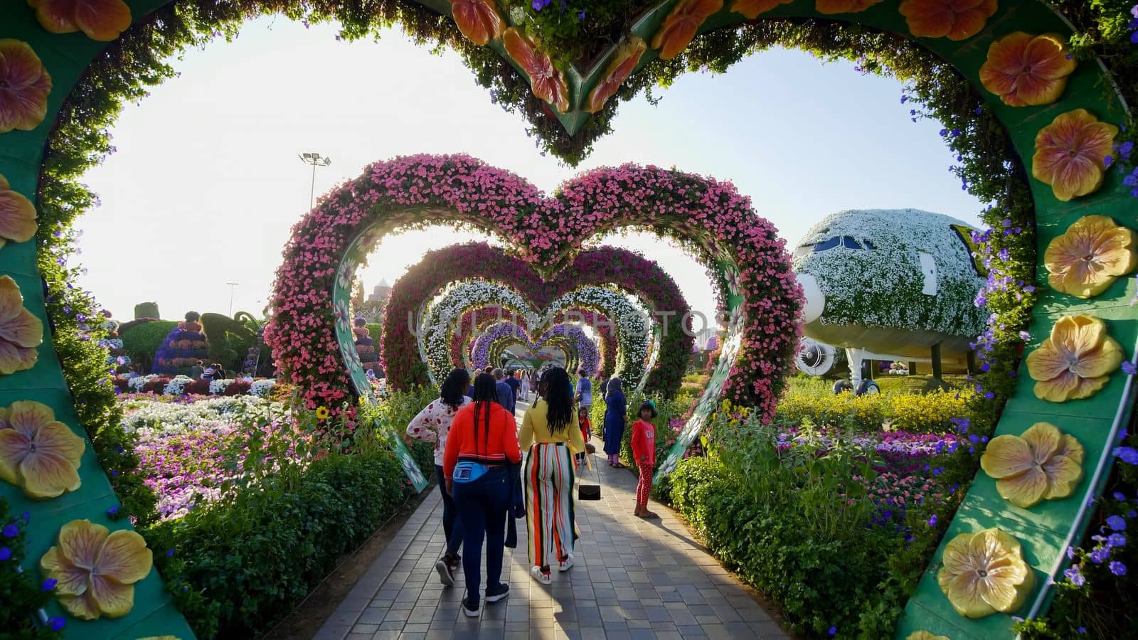 Heart shaped flower beds at the Alley of Hearts. Dubai Miracle Garden is famous for its extraordinary flower installations. A couple of people walking around at the park.