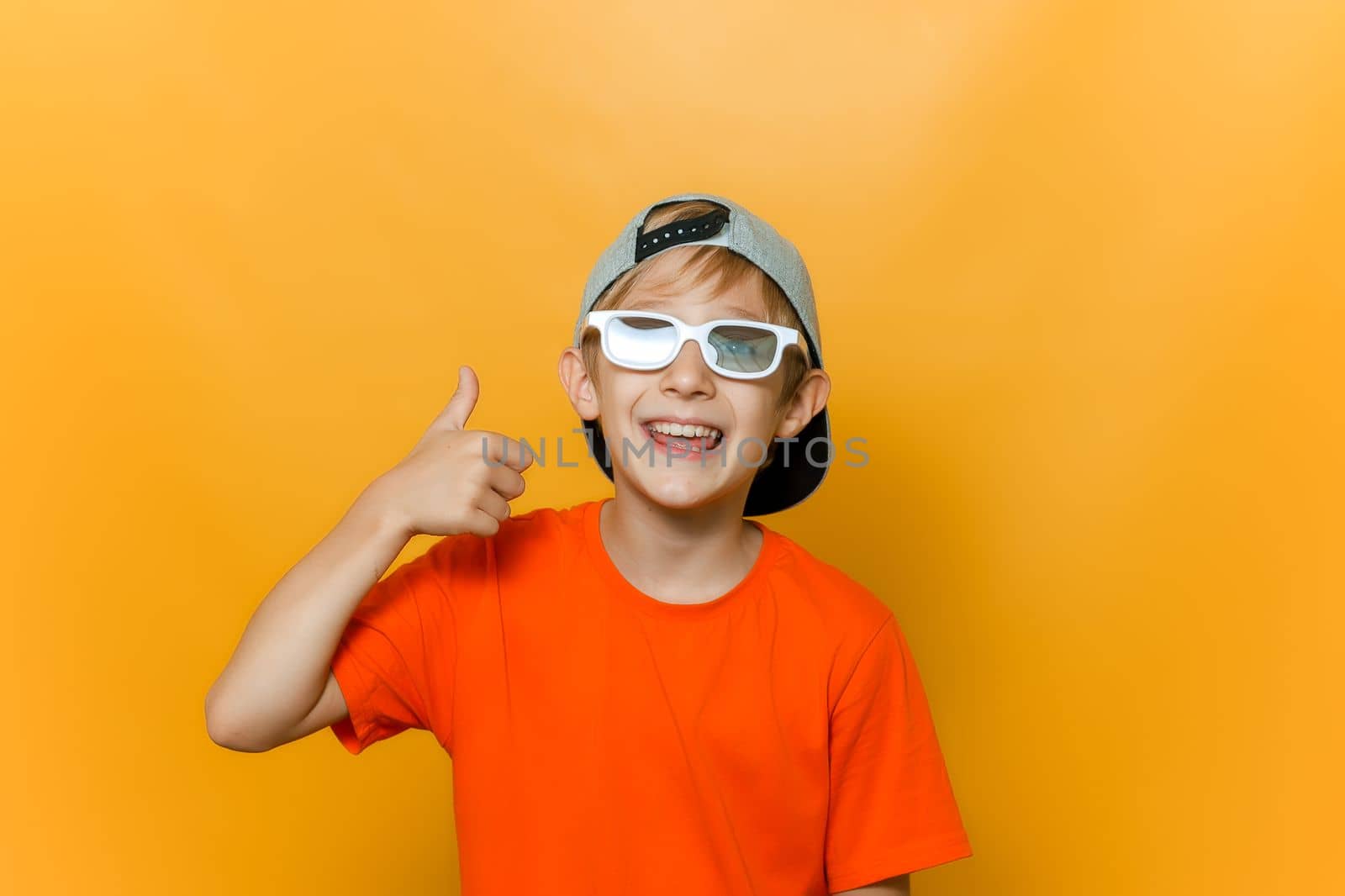 a child in a cap and glasses for watching movies shows a thumbs up and laughs merrily by RomanChoknadii