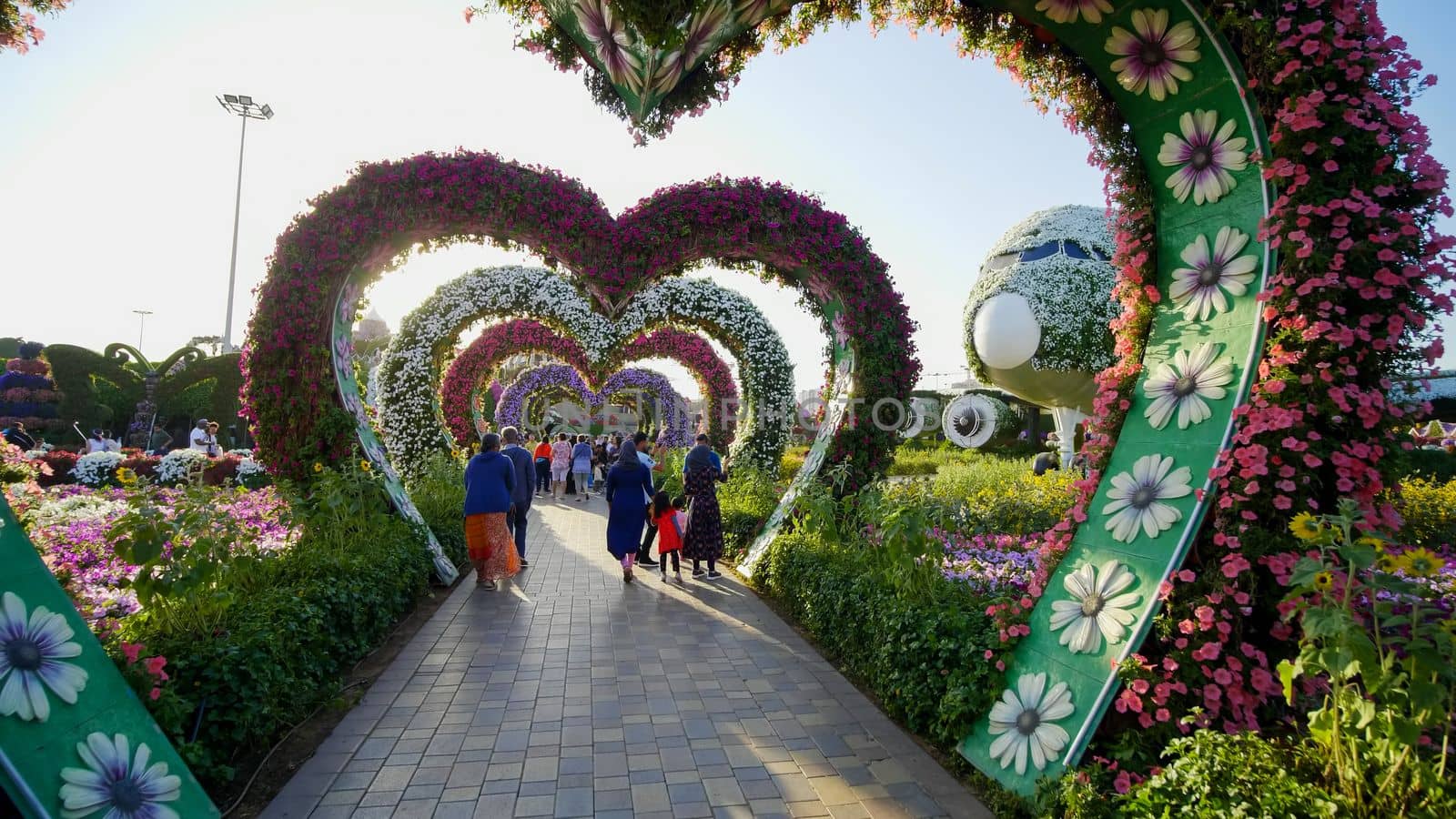 Heart shaped flower beds at the Alley of Hearts. Dubai Miracle Garden is famous for its extraordinary flower installations. A couple of people walking around at the park.