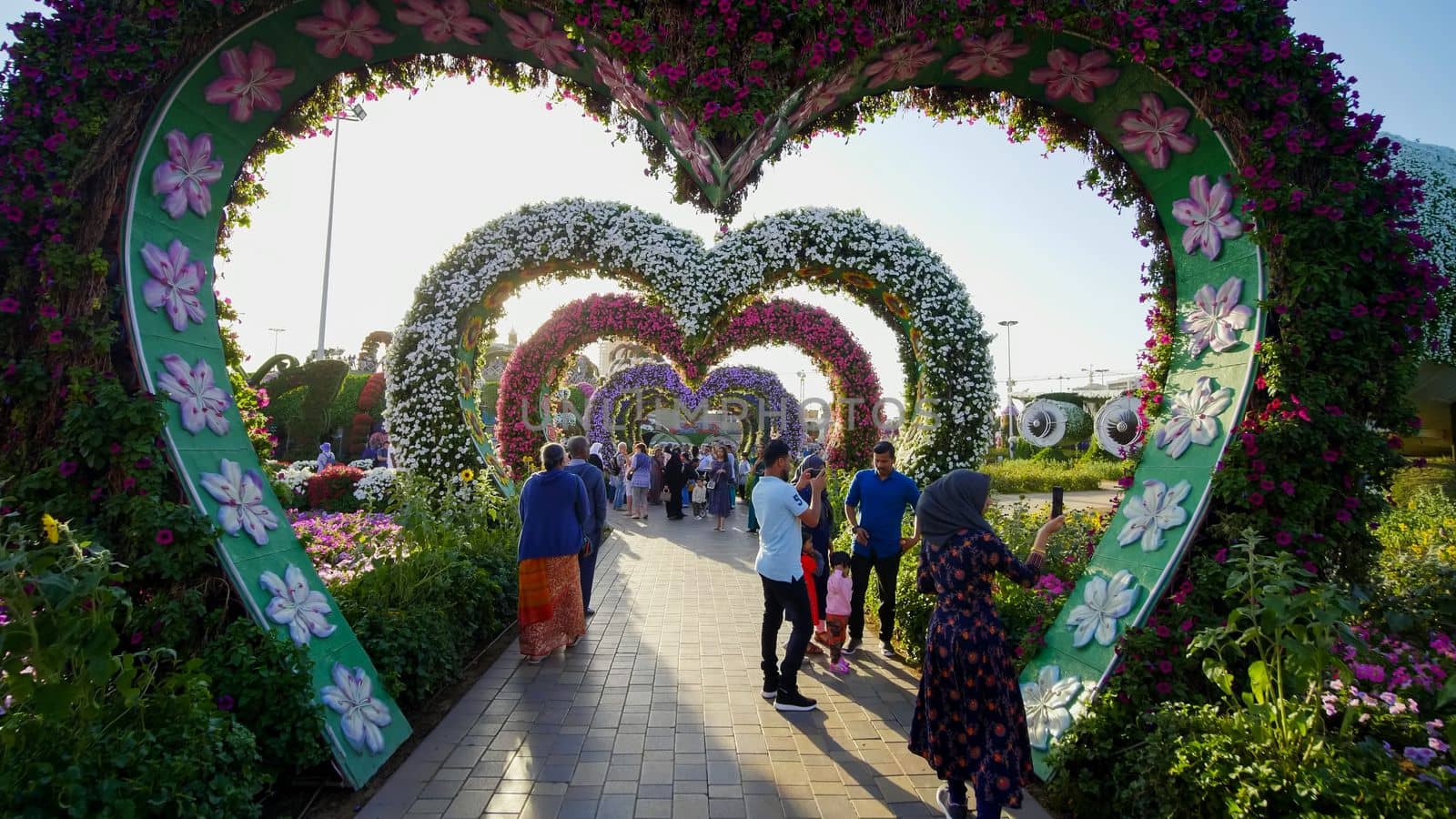 Heart shaped flower beds at the Alley of Hearts. Dubai Miracle Garden is famous for its extraordinary flower installations. A couple of people walking around at the park.