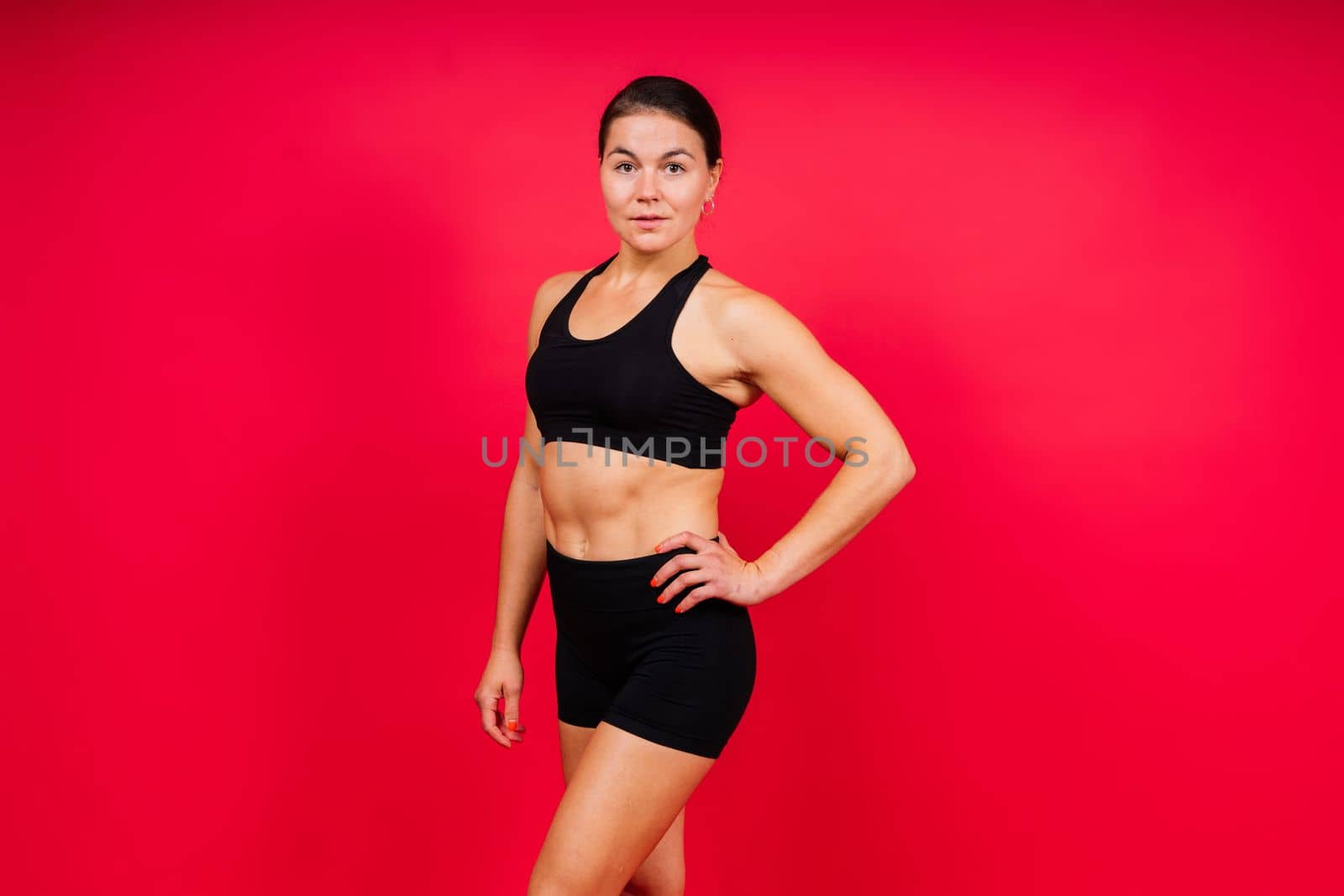 Strong sportswoman in boxing gloves prepared high kick. Isolated on a white, red, yellow background