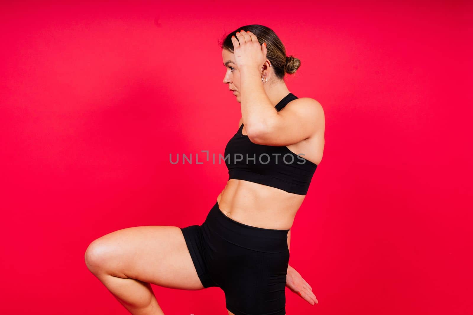 Strong sportswoman in boxing gloves prepared high kick. Isolated on a white, red, yellow background