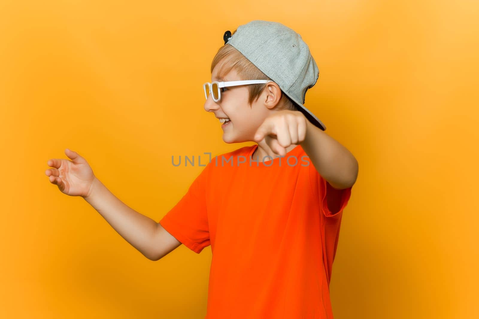 a child wearing glasses for watching movies looks to the side and points his finger forward and mocks by RomanChoknadii
