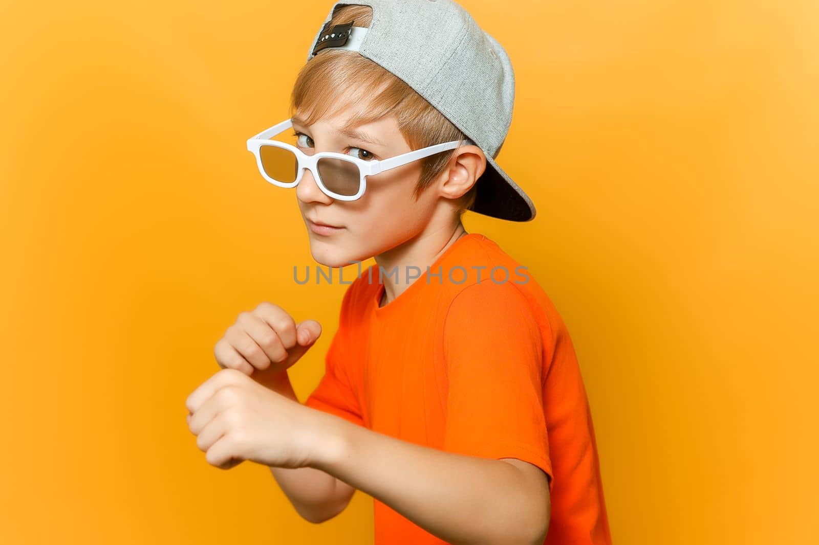 a child in glasses for watching movies clenched his fists and looks askance at the camera