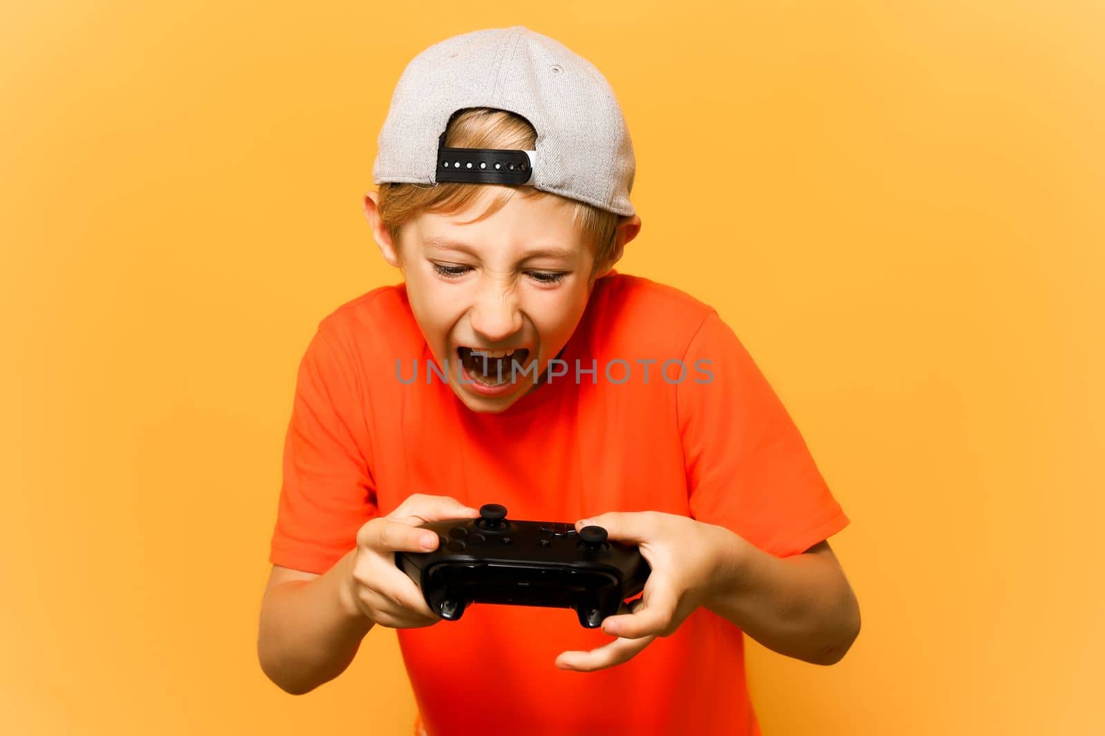 a gamer boy holds a gamepad in his hands and actively presses the emotion buttons in the game