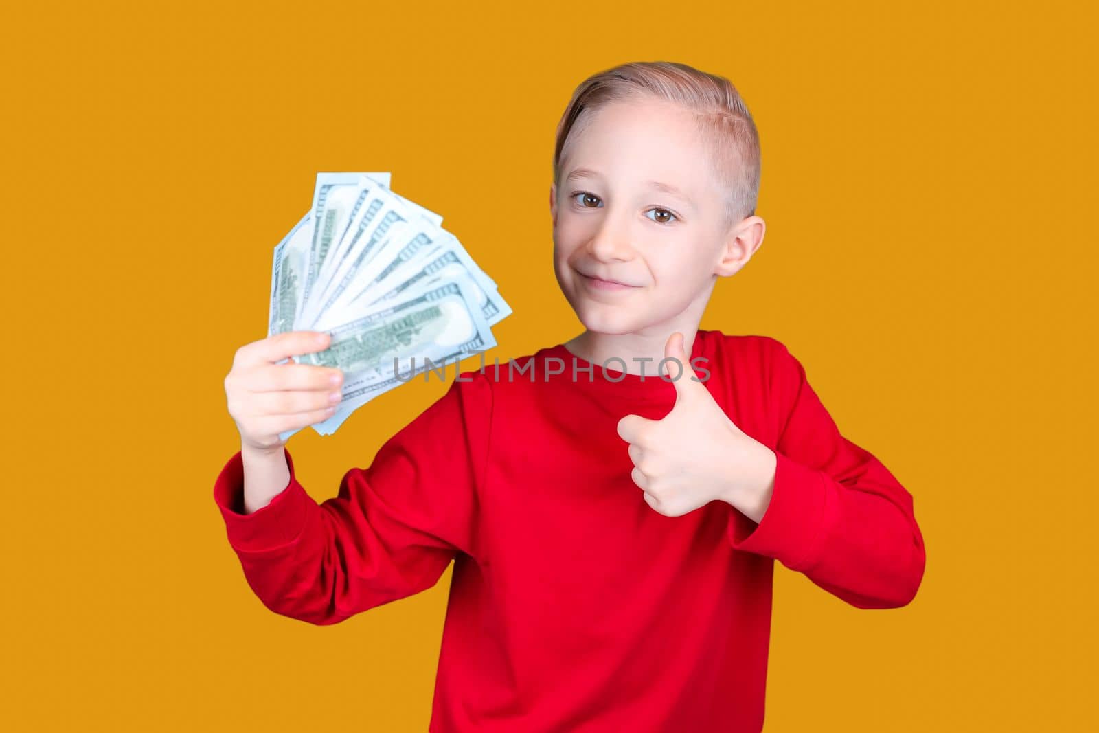 happy child holds banknotes in his hand and gives a thumbs up