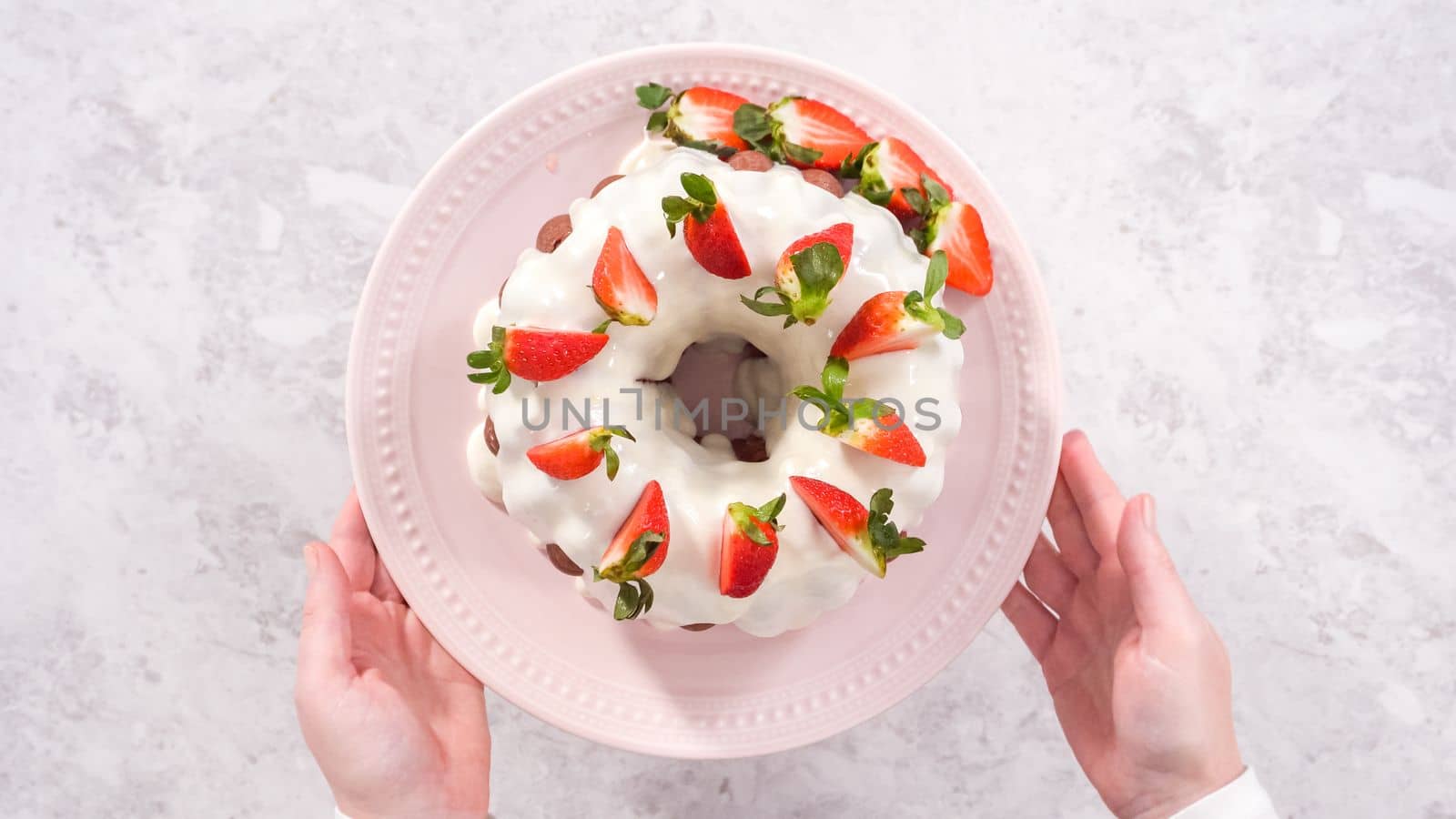 Flat lay. Step by step. Decorating freshly baked red velvet bundt cake with organic strawberries.