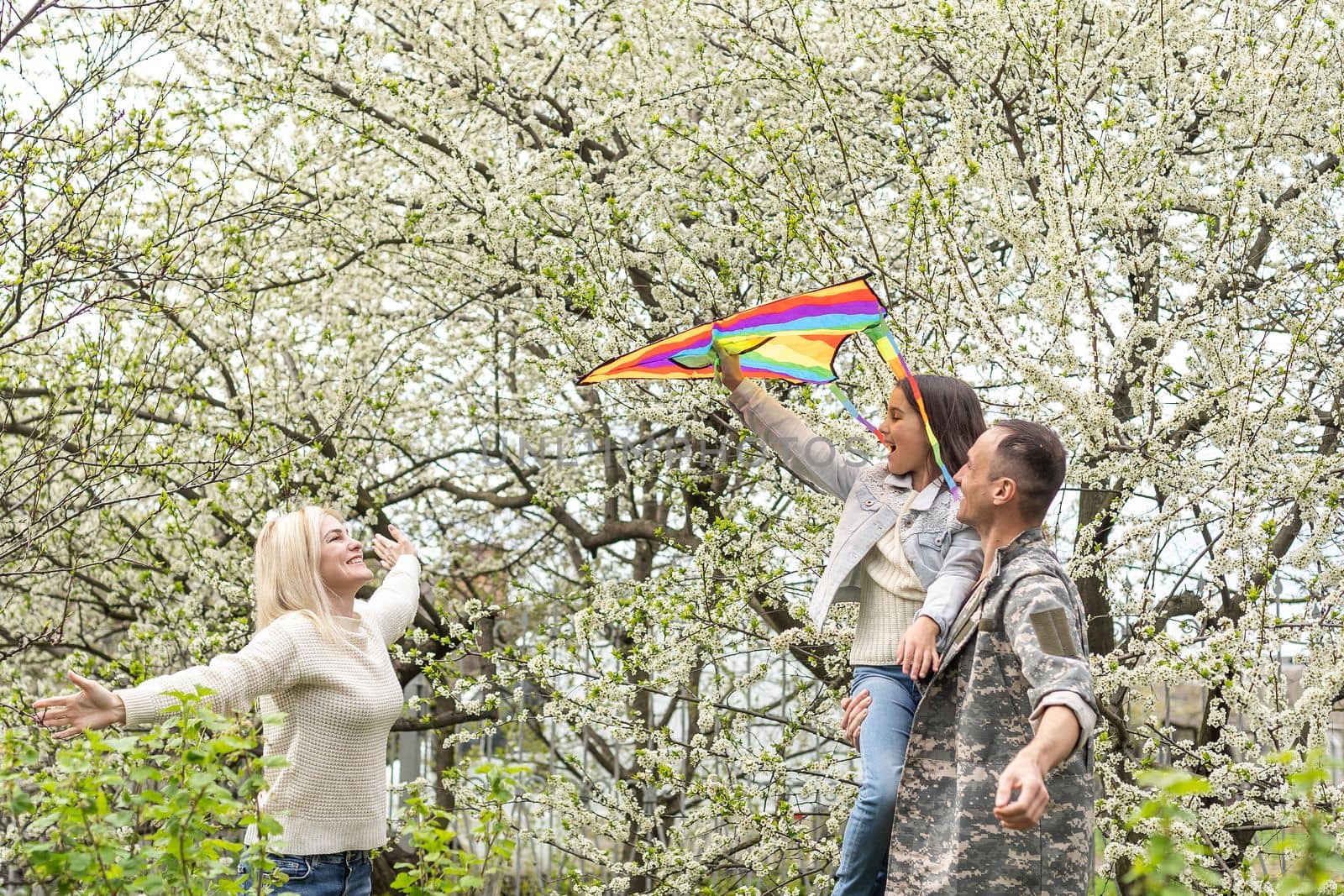 Soldier is meeting his family outdoors. Happy reunion of father and kids on the grass.