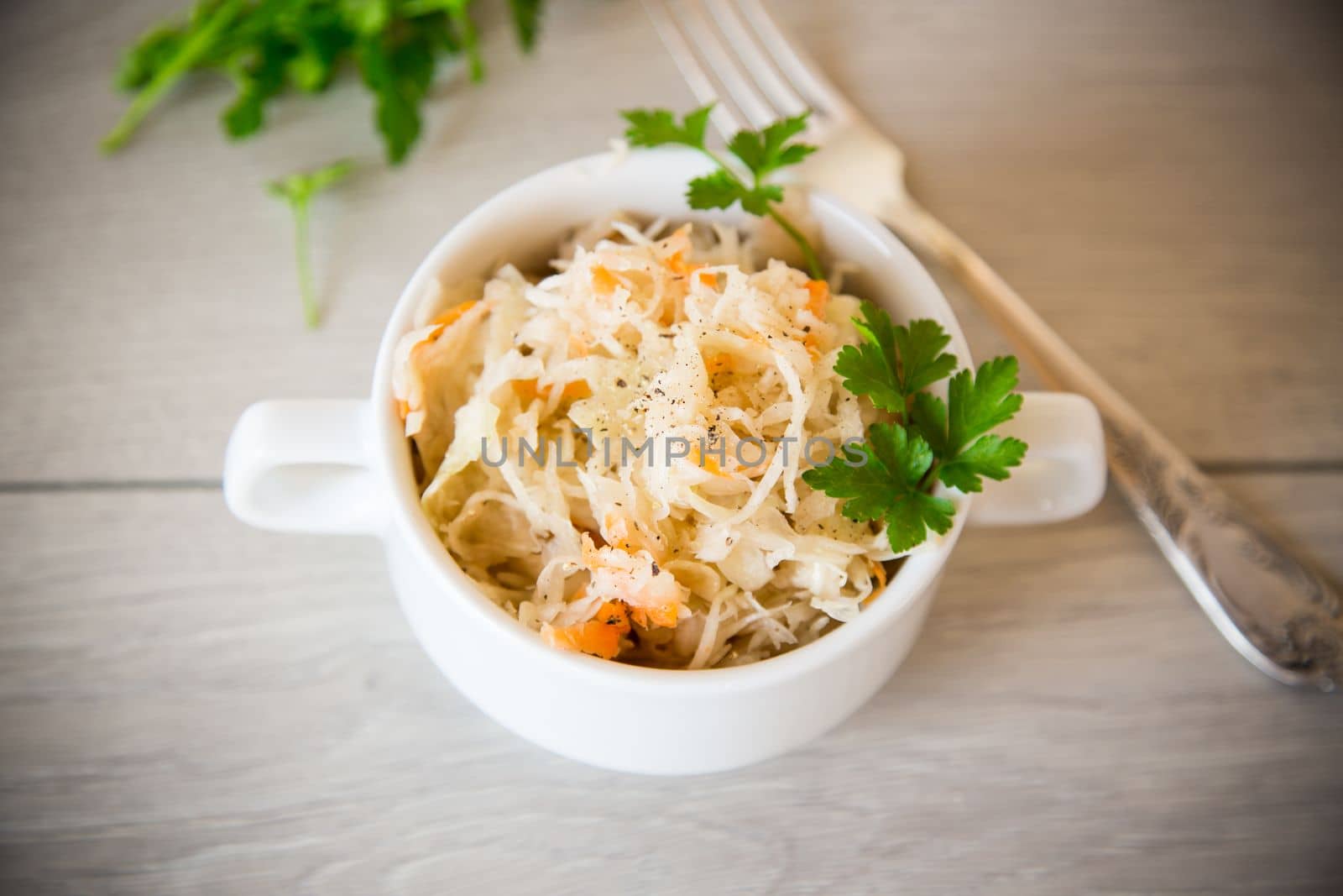 sauerkraut with carrots and spices in a bowl on a wooden table.